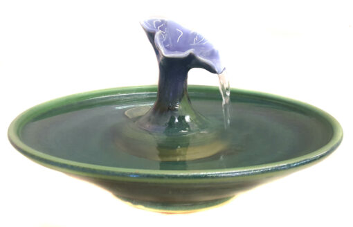 A gorgeous cat fountain in a Petunia design with a Lavender Blue blossom and a Deep Spruce fountain bowl. Water fills the blossom and streams into the bowl. Excellent for long hair cats. * 3.25 inches high by 12" in diameter at the widest * 8 cup capacity * 100% food-safe & tested ceramics * Pleasant water sounds or quiet, as you choose * Very easy to clean * Can be adapted for use in EU outlets. European pumps can be purchased via the following link: https://www.etsy.com/listing/384659996/installation-of-european-2202140v-pump?ga_search_query=EU&ref=shop_items_search_18 This fountain does not take any of the Cat Taps , the Serenity flow or the copper Waterleaf. What is included: